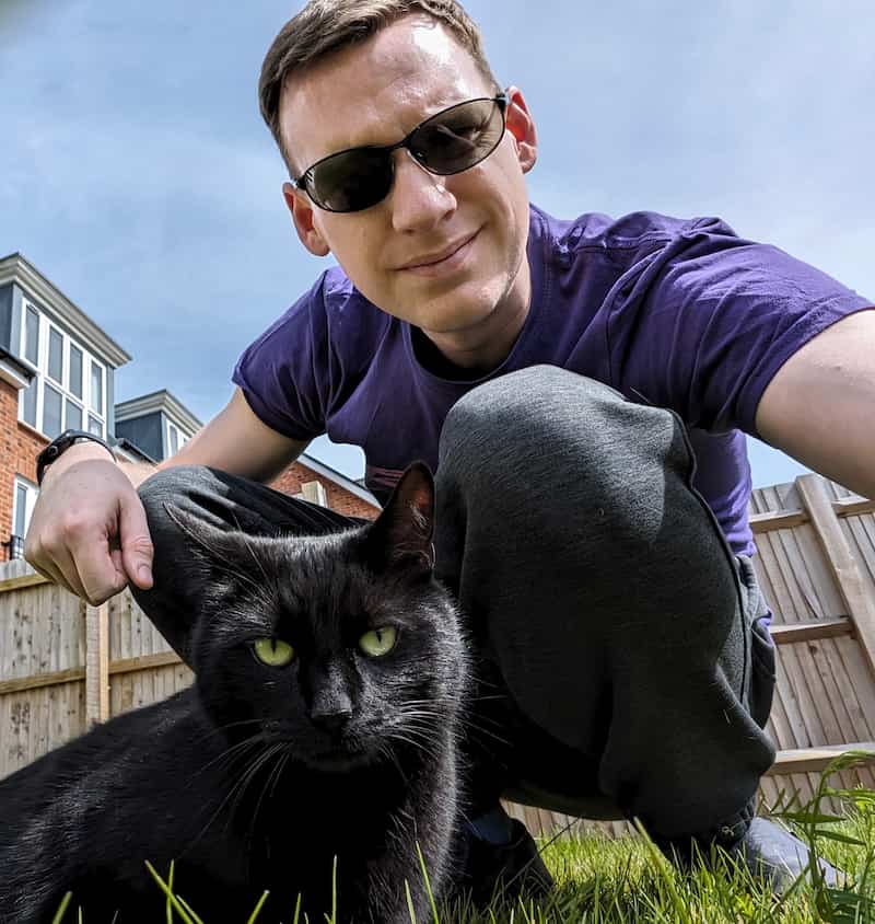 Jake Archibald in a garden with a black cat